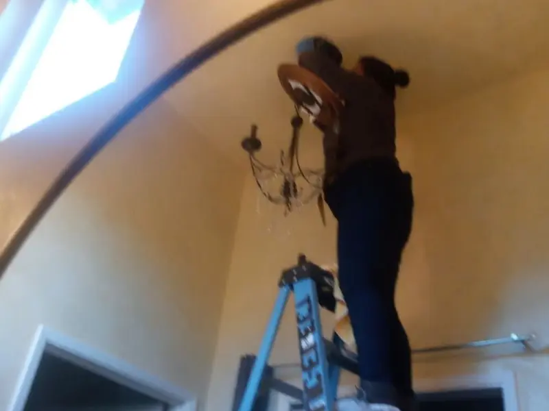 Electrician installing a chandelier in a Pittsburg residence